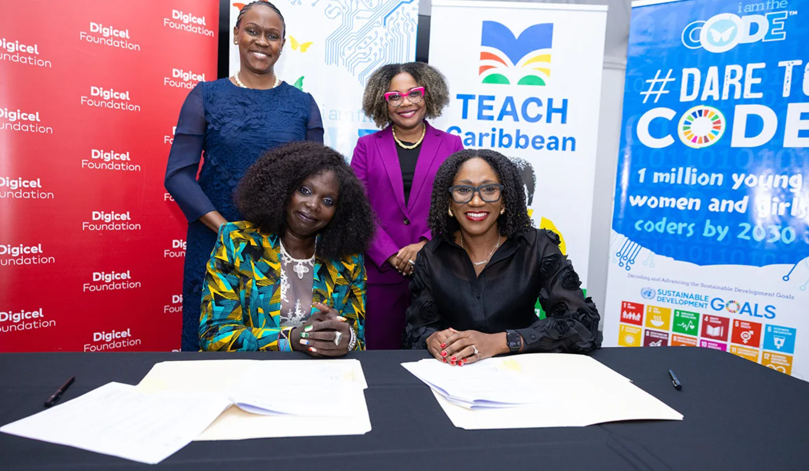 Four participants at the original iamtheCODE Caribbean MOU signing, with partnership documents on the table